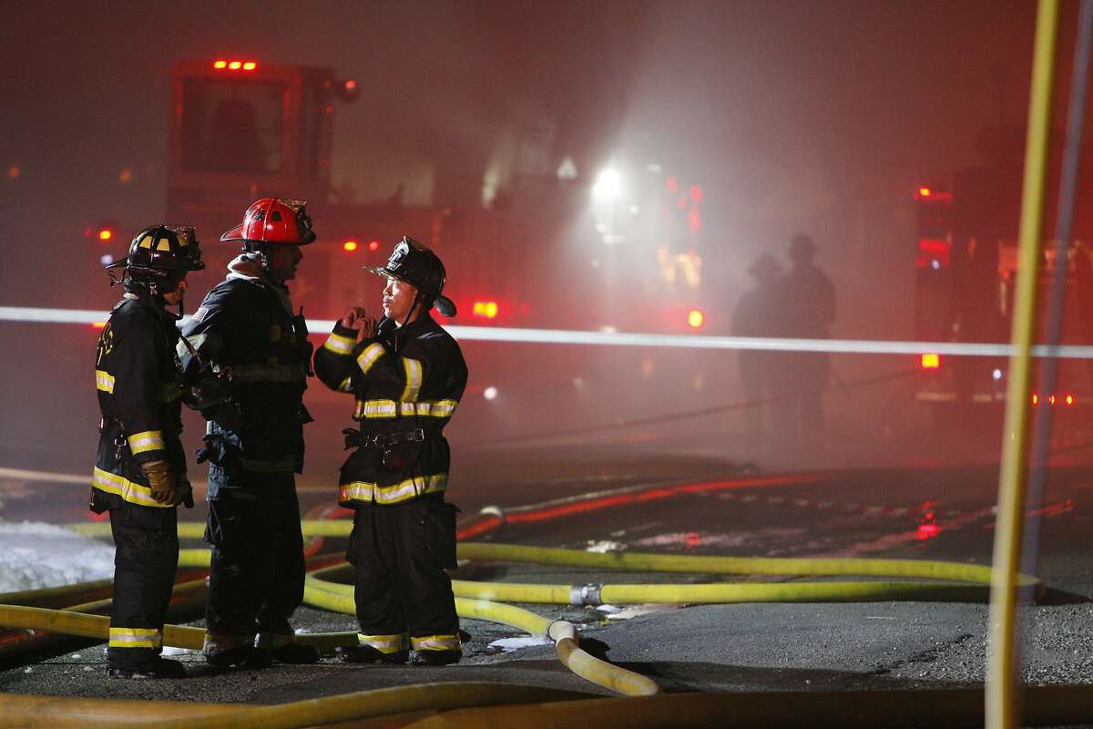 Firefighters talk to one another during a fire on the 1800 block of Second Street on April 12, 2014 in Berkeley, Calif.