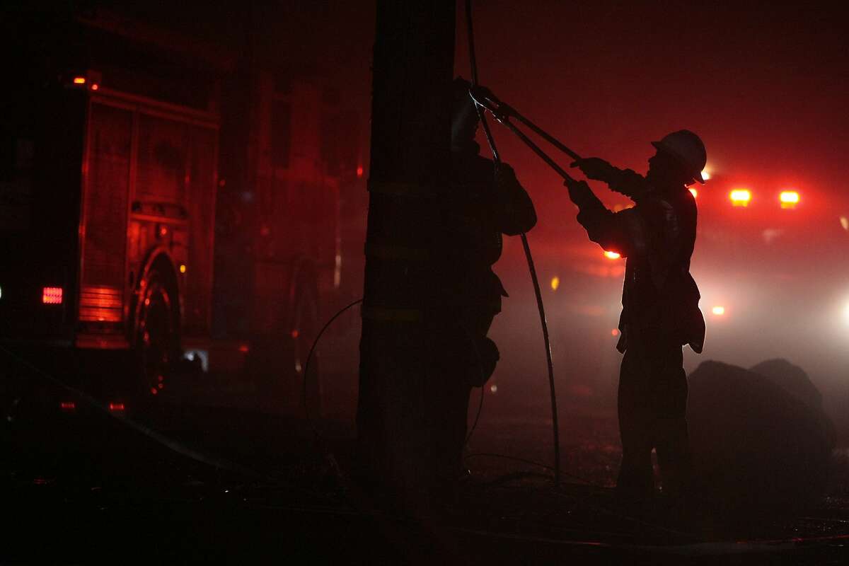 A worker cuts a thick cable during a fire on the 1800 block of Second Street on April 12, 2014 in Berkeley, Calif.