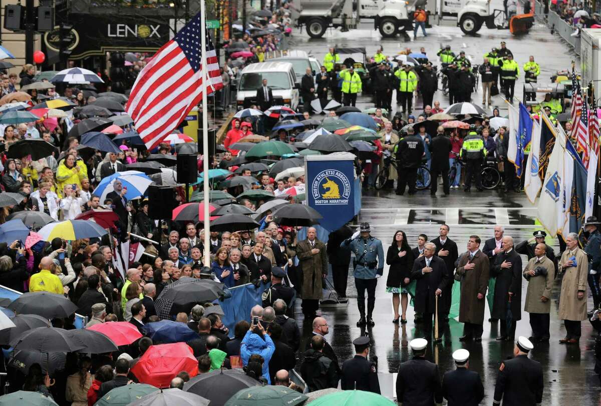 Survivors, officials, first responders and guests pause as the flag is raised at the finish line during a tribute in honor of the one year anniversary of the Boston Marathon bombings, Tuesday, April 15, 2014 in Boston. (AP Photo/Charles Krupa) ORG XMIT: MACK104
