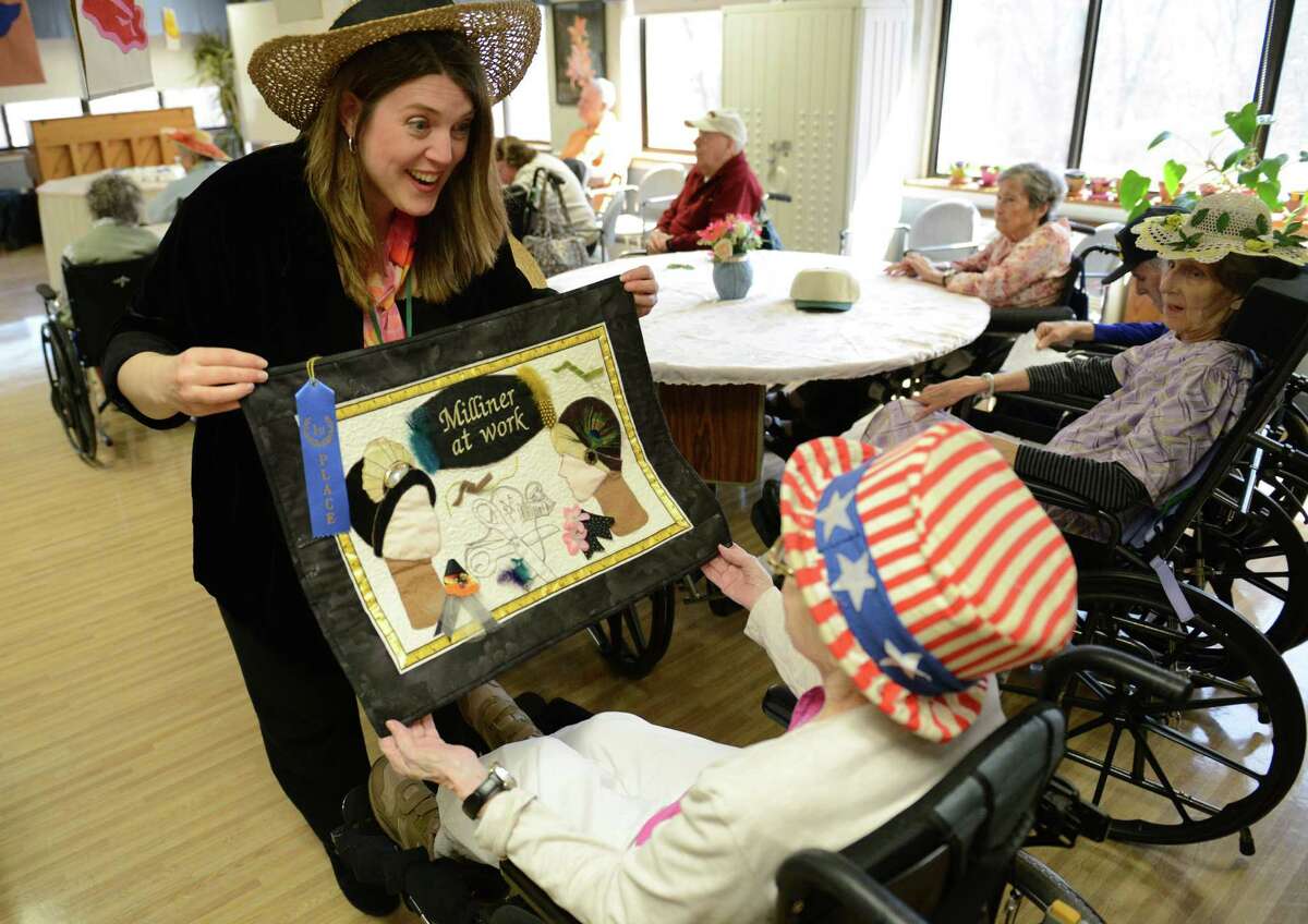 Certified Therapeutic Recreation Specialist Holly Taylor-Fry shows hat-related art to Mary Salvato, of Danbury, during the Hat Day Celebration at the Filosa Hancock Hall in Danbury, Conn. Thursday, April 17, 2014. Members of the Danbury Museum spoke with the crowd about the history of Hat City. 