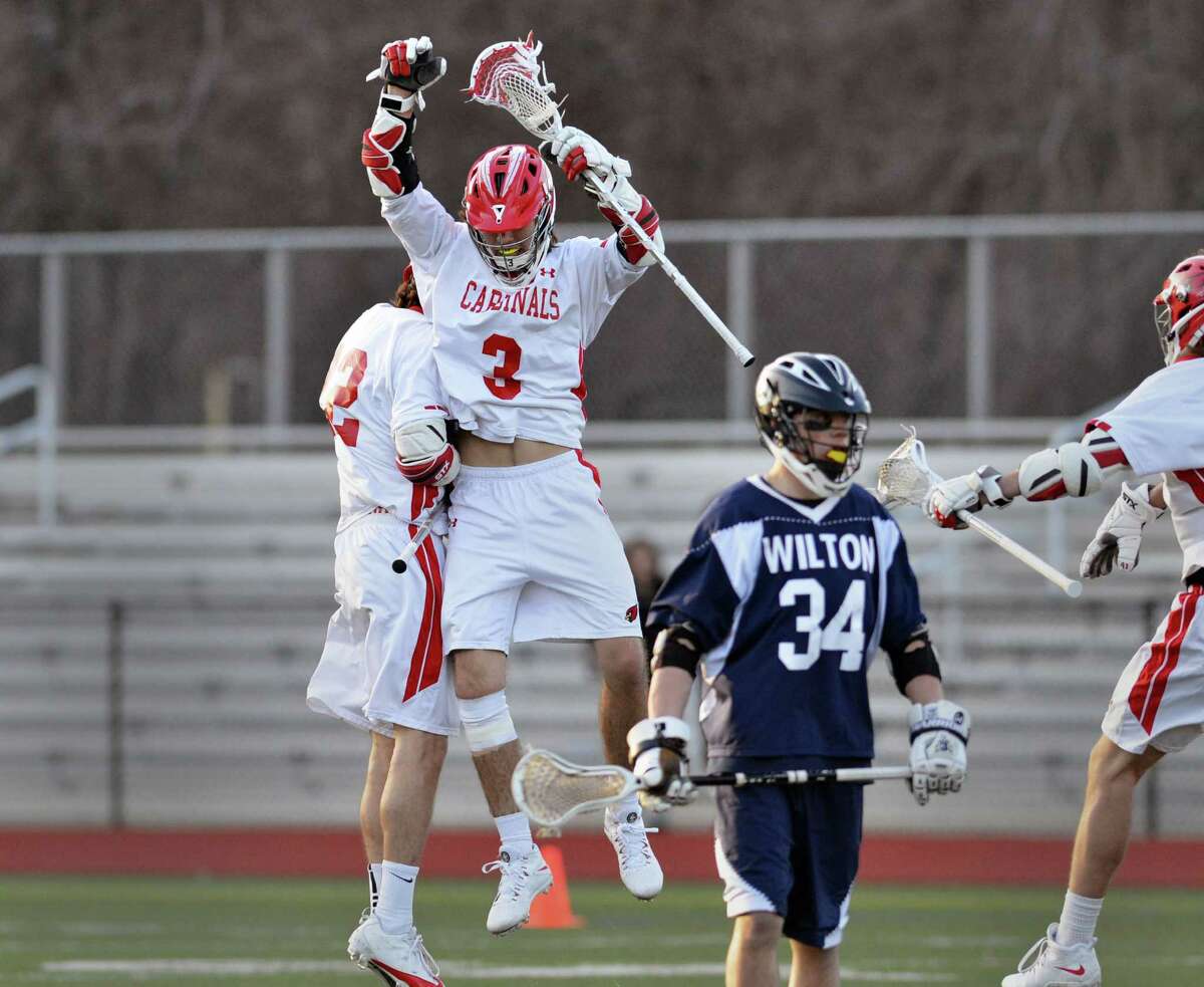 At center, Kyle Foote (#3) of Greenwich celebrates his goal just before the half with teammate Jamie Paradise, left, while Wilton's Ryan Sullivan (#34) looks away during the high school lacrosse match between Greenwich High School and Wilton High School at Greenwich, Thursday night, April 17, 2014. Greenwich defeated Wilton,18-7.