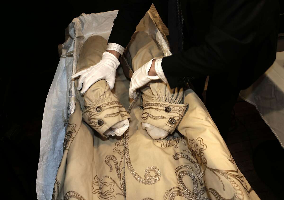 Fashion historian Kevin Jones uses gloved hands to unpack the ornate coat that was paired with the dress from 1906, at John's Grill in San Francisco, Calif., on Thursday April 17, 2014. A beautiful, fragile dress purchased by a San Francisco lady to wear to the opera in 1906 has surfaced after years in a local historian's garage.