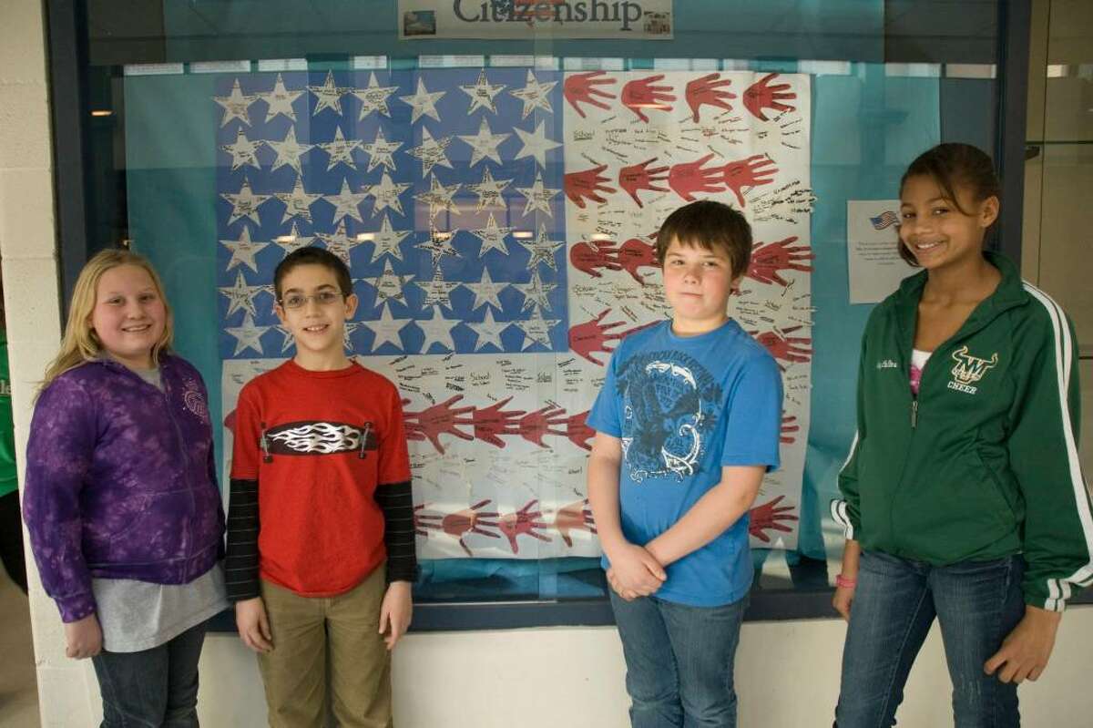 From left, fith graders Kendall Stewart, Nicholas Santarelli, James Cramer, and Ivey Collins stand in front of the community flag they made in class at Sarah Noble School in New Milford.