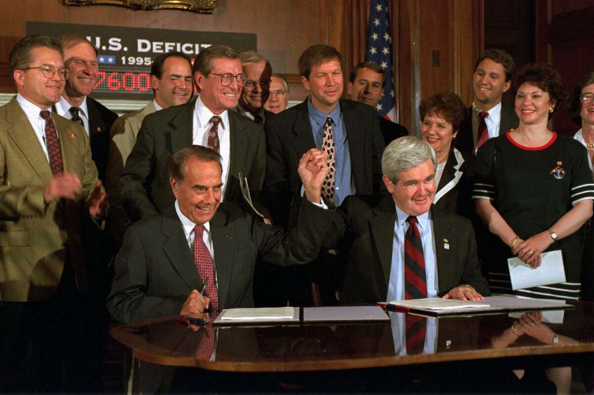 Bob Dole, left, and House Speaker Newt Gingrich clasped hands during a Capitol Hill news conference in 1995 to sign the Republican's budget resolution. Gingrich's plan retained the spending cuts and tax increases from Bush's 1990 budget agreement.