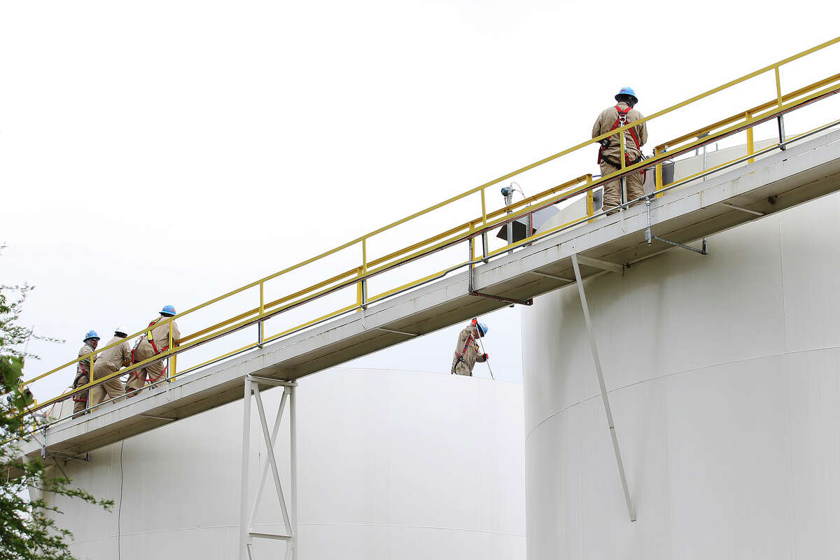 Workers are seen atop storage tanks at the Calumet Specialty Products Partners plant near the Mission Reach of the San Antonio River, Thursday, April 17, 2014.