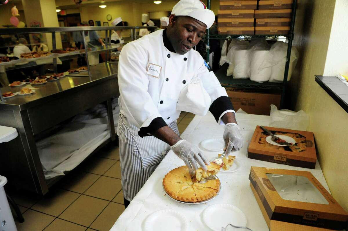 Kinimo Ngoran, a chef at the Capital City Rescue Mission, dishes out apple pie during Easter dinner at the mission on Sunday, April 20, 2014, in Albany, N.Y.