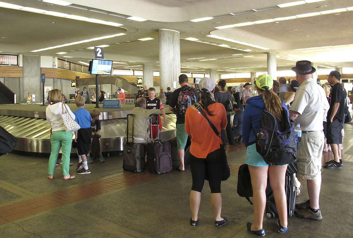 Passengers from Hawaiian Airlines Flight 45 wait for their baggage after arriving from San Jose, Calif., in Kahului Airport in Kahului, Hawaii, on Monday, April 21, 2014. A 15-year-old boy on Sunday scrambled over an airport fence, crossed a tarmac and climbed into a jetliner's wheel well, then flew for five freezing hours to Hawaii on a misadventure that forced authorities to take a hard look at the security system that protects the nation's airline fleet. (AP Photo/Oskar Garcia)