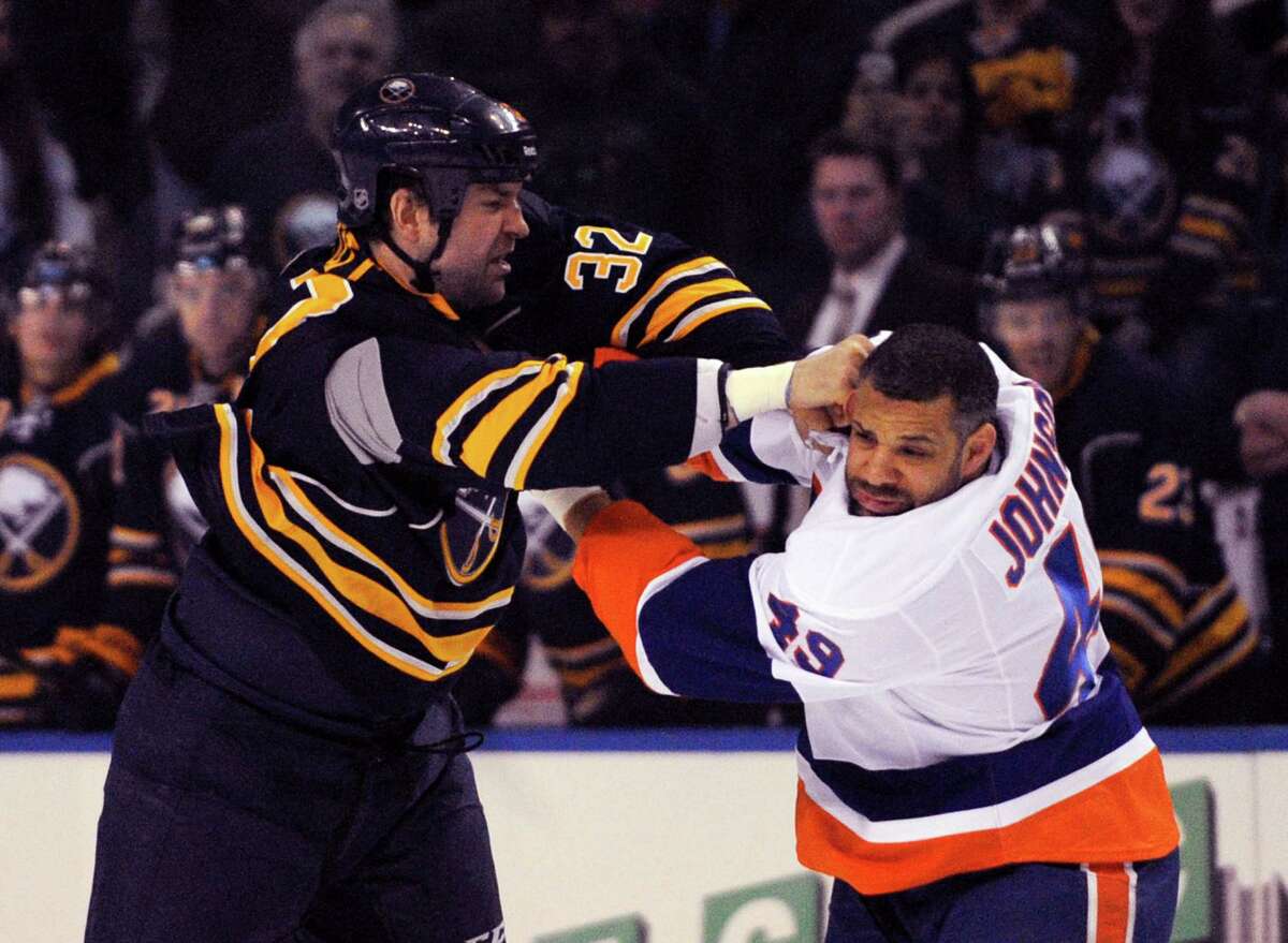 Buffalo Sabres left winger John Scott (32) lands a punch to the side of the head on New York Islanders right winger Justin Johnson (49) during the first period of an NHL hockey game in Buffalo, N.Y., Sunday April 13, 2014. (AP Photo/Gary Wiepert)
