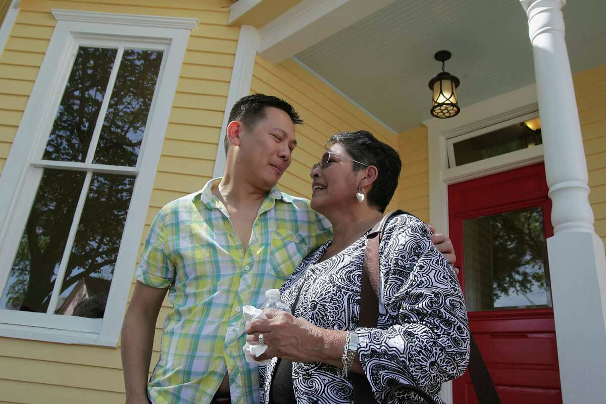 Dominic Yap, who is buying old homes in the First Ward but remodeling them instead of tearing them down, shows Gloria Perez the house she sold him. Yap renovated the interior and painted the exterior a sunny yellow.