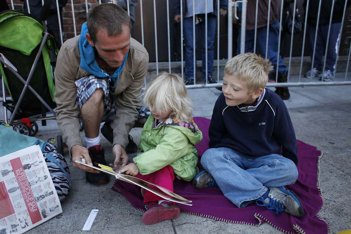 Chris Joslyn reads to his daughter Charley, 2, in line for "Bridges to Health," a free healthcare event, as his son Christopher, 6, watches outside the San Francisco Armory on April 23, 2014 in San Francisco, Calif. Bridges to Health is a two day event in San Francisco (with a third day in Oakland) that provides free medical, dental, vision and other health care to at-risk populations. Joslyn, who is currently living in shelters in San Francisco, was hoping to get dental care for his son and himself.