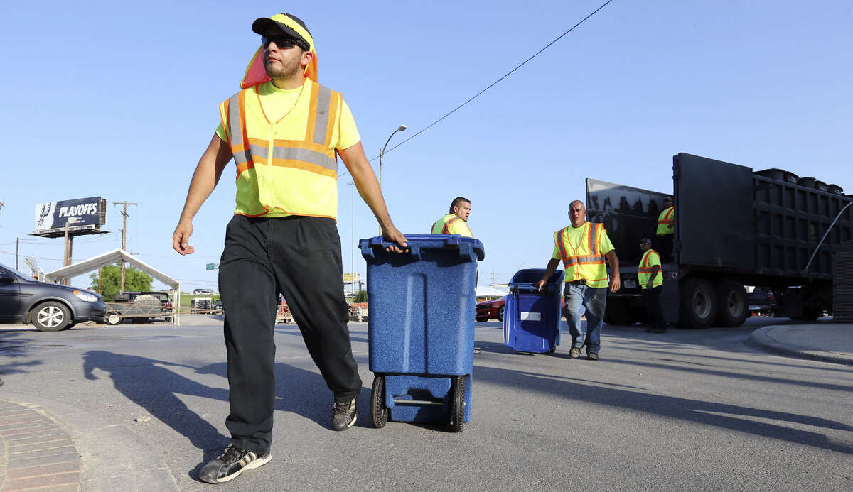 City workers Rudy Esquivel (from left), Raul Pena, Henry Flores and others set up recycling and trash bins Thursday on Broadway.