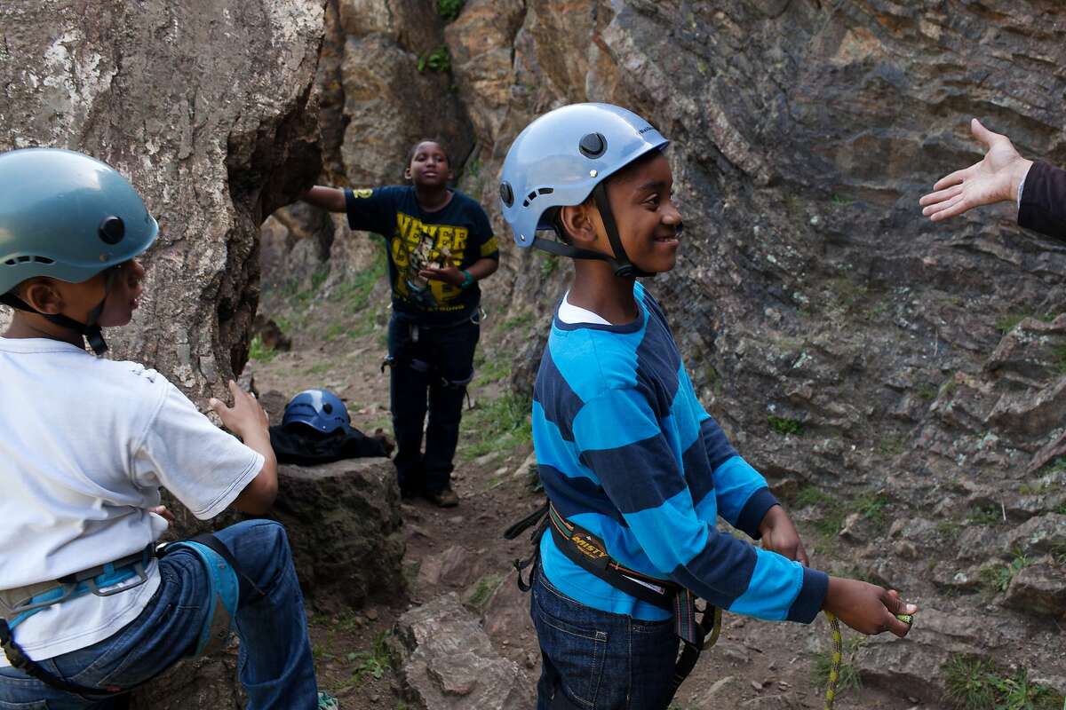 Jovian, 10, James, 12, and James, 11, listen to therapist Clifton Hicks, 50, before a rock climb during an adventure-based psychotherapy program for youth who have experienced trauma and PTSD in Glen Canyon Park in San Francisco, Calif. on Tuesday, April 15, 2014. This program is one of many efforts to address community and home-based trauma and violence.