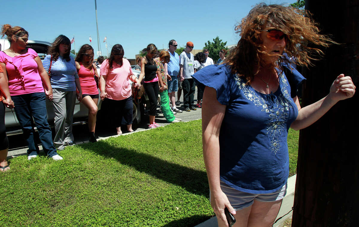 Mary Moore (right, foreground) leads a group of parents in prayer Tuesday April 29, 2014 in front of Madison High School after the school declared itself under lockdown for the second day in a row. Weapons were found at the school yesterday.