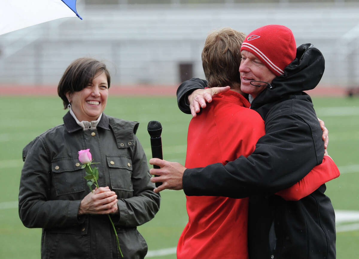 Greenwich High School senior runner Mark Jarombek, center, gets a hug from his coach, Tom Aberle, right, as Jarombek's mother, Liza Jarombek, left, looks on as seniors were honored before the start of the high school track meet at Greenwich High School, Tuesday, April 29, 2014.