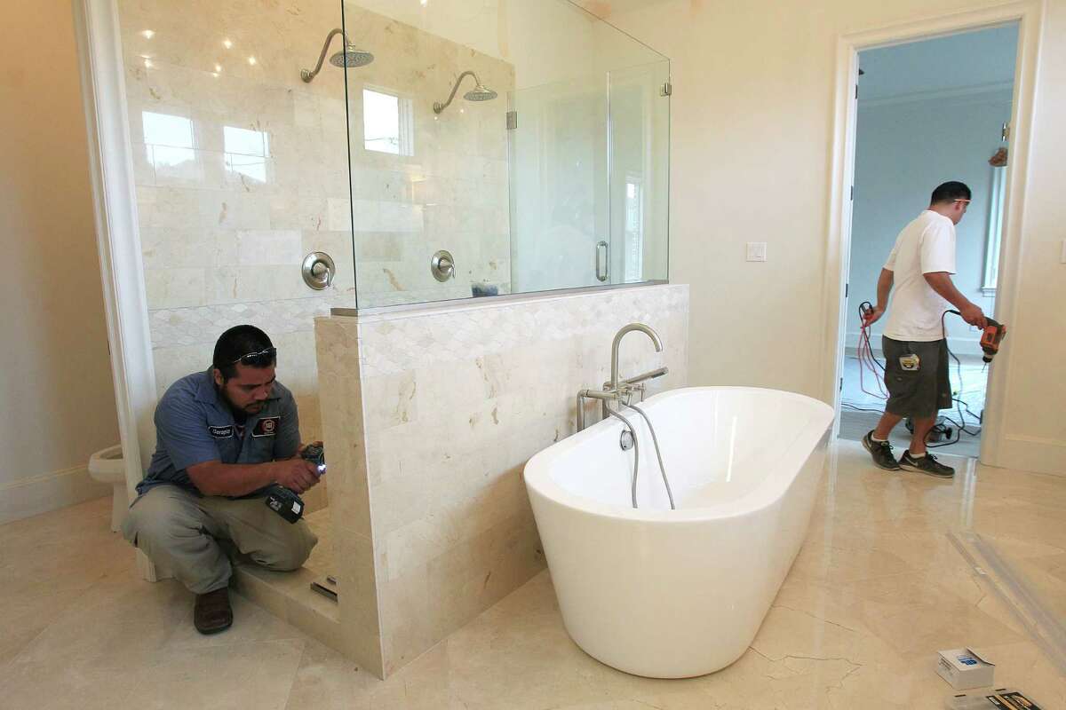 Serapio Loeta and Carlos Rocha work on the master bathroom in a home built by Horace Homes in the West University area on April 21, 2014, in Houston, Tx. ( Mayra Beltran / Houston Chronicle )