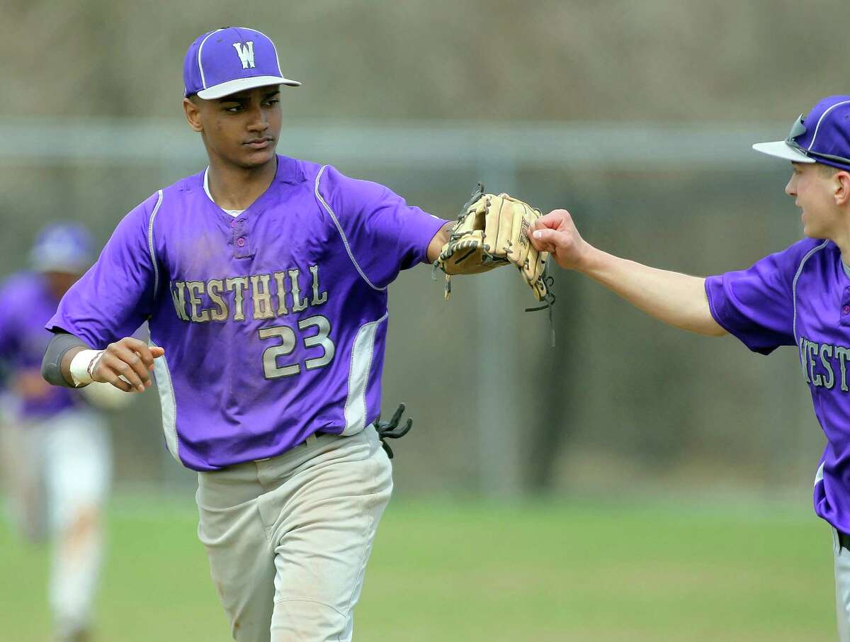 Westhill High School shortstop (#23) Ronald Jackson gets a high five from a teammate following a 5-4 win over Ridgefield High School on Monday, April 14, 2014 in Stamford, Conn.