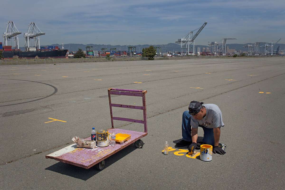Ricardo Gutierrez paints in preparation for the Alameda Point Antiques Faire in Alameda, Calif. on Thursday, May 1, 2014. The city of Alameda says it will build 800 apartments and condos on the bay front, a move that pits the city against its own law prohibiting high-density housing.