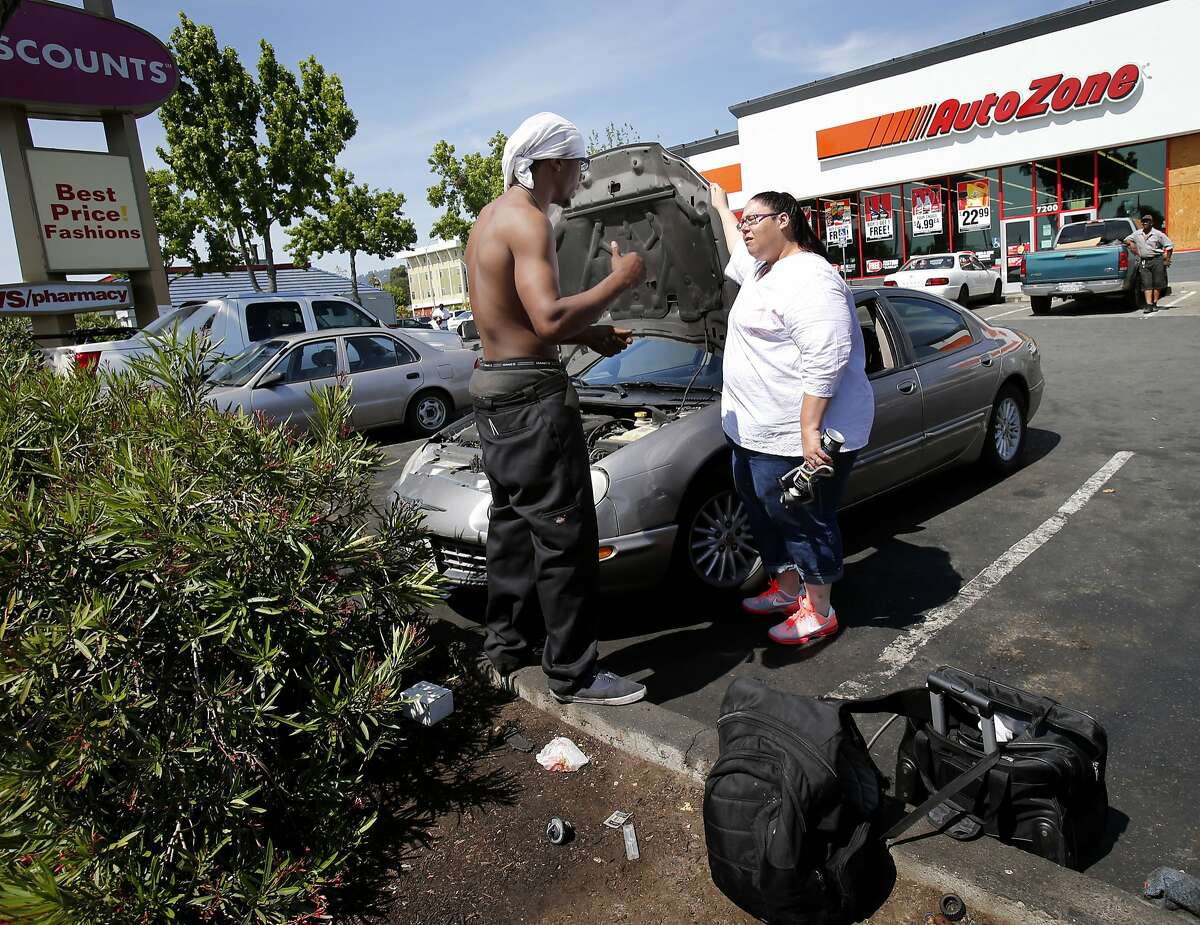 A mechanic named Solo Bolo (left) talks with a customer named Rene Roche about her air conditioning problem Wednesday April 30, 2014 in Oakland, Calif. His tools are in the foreground. A group of automobile mechanics work in the parking lot of the AutoZone at Bancroft and 73rd Avenue are doing various repairs for a fraction of the cost of a real-live certified mechanic.
