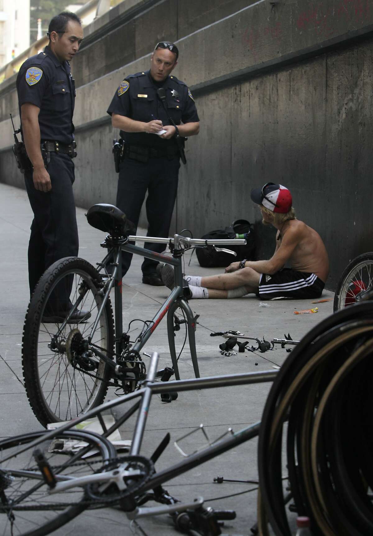 Police officers Gary Cheng (left) and Matt Friedman question an unidentified man about a bicycle he was dismantling below the Central Freeway on Duboce Avenue in San Francisco, Calif. on Thursday, May 1, 2014. The bicycle was not reported stolen, so the man were released. While police suspect many of the bicycles may be stolen, few arrests are made since owners are reluctant to report them as stolen.