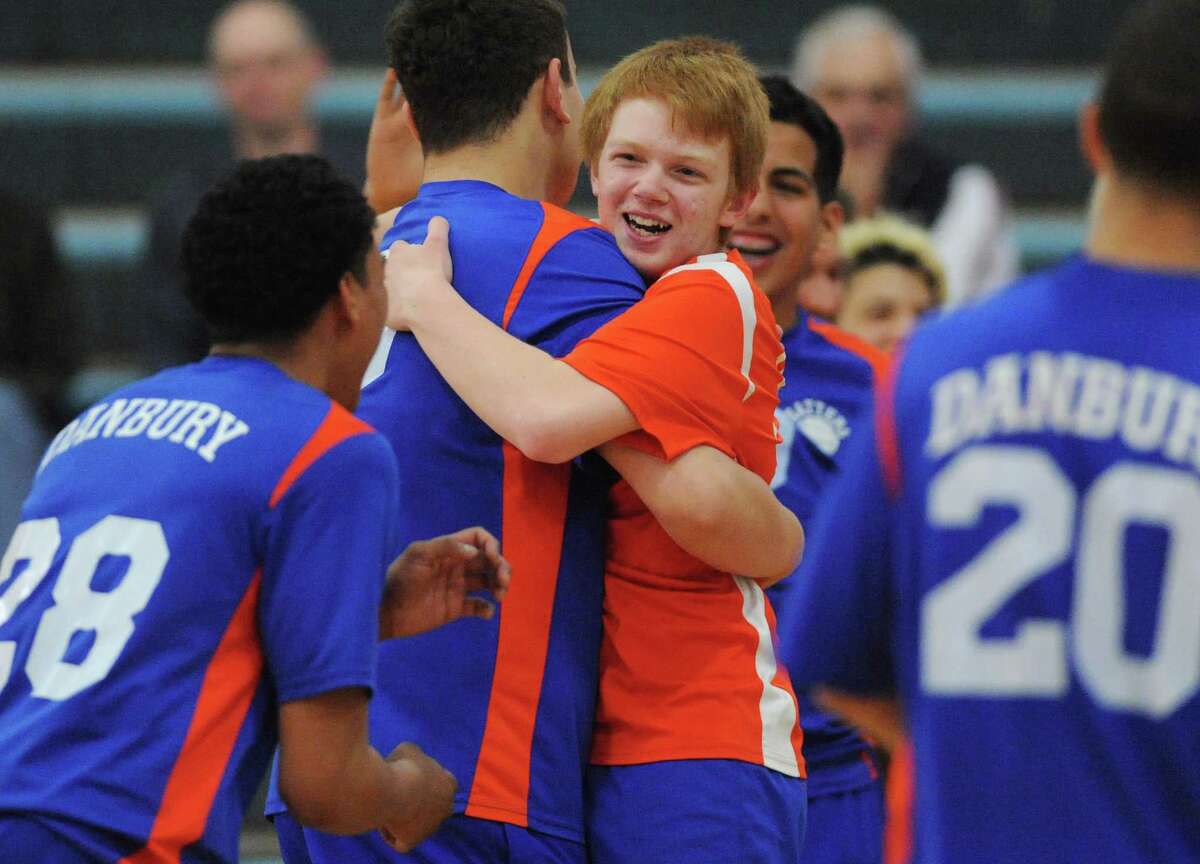 Danbury volleyball player Tom Demouth, wearing an orange setter's shirt, is hugged by teammates in his team's 3-1 win over Greenwich at Danbury High School in Danbury, Conn. Friday, May 2, 2014.