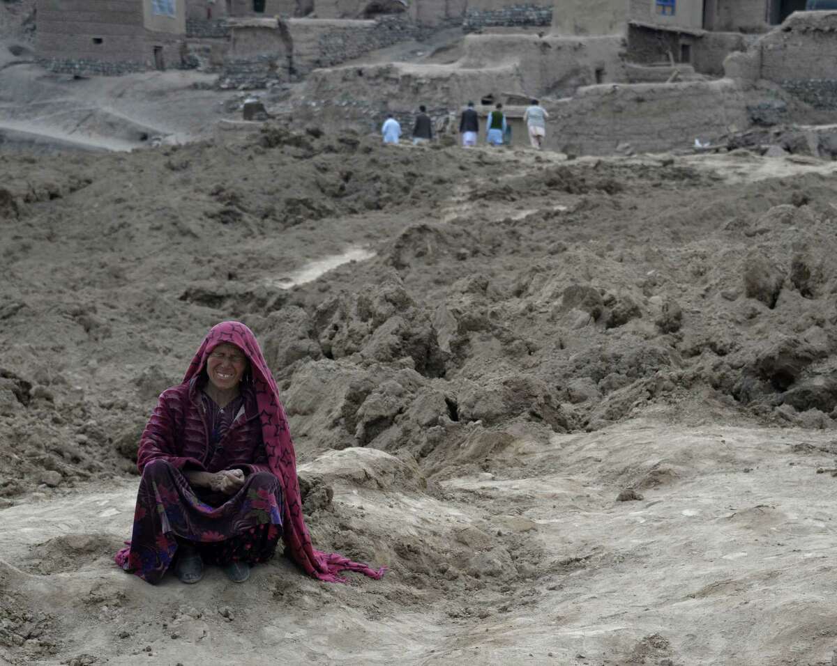 An Afghan cries as she sits on top of mud in Badakhshan province, where a massive landslide buried the village of Abi Barak. Rescuers searched in vain for survivors.