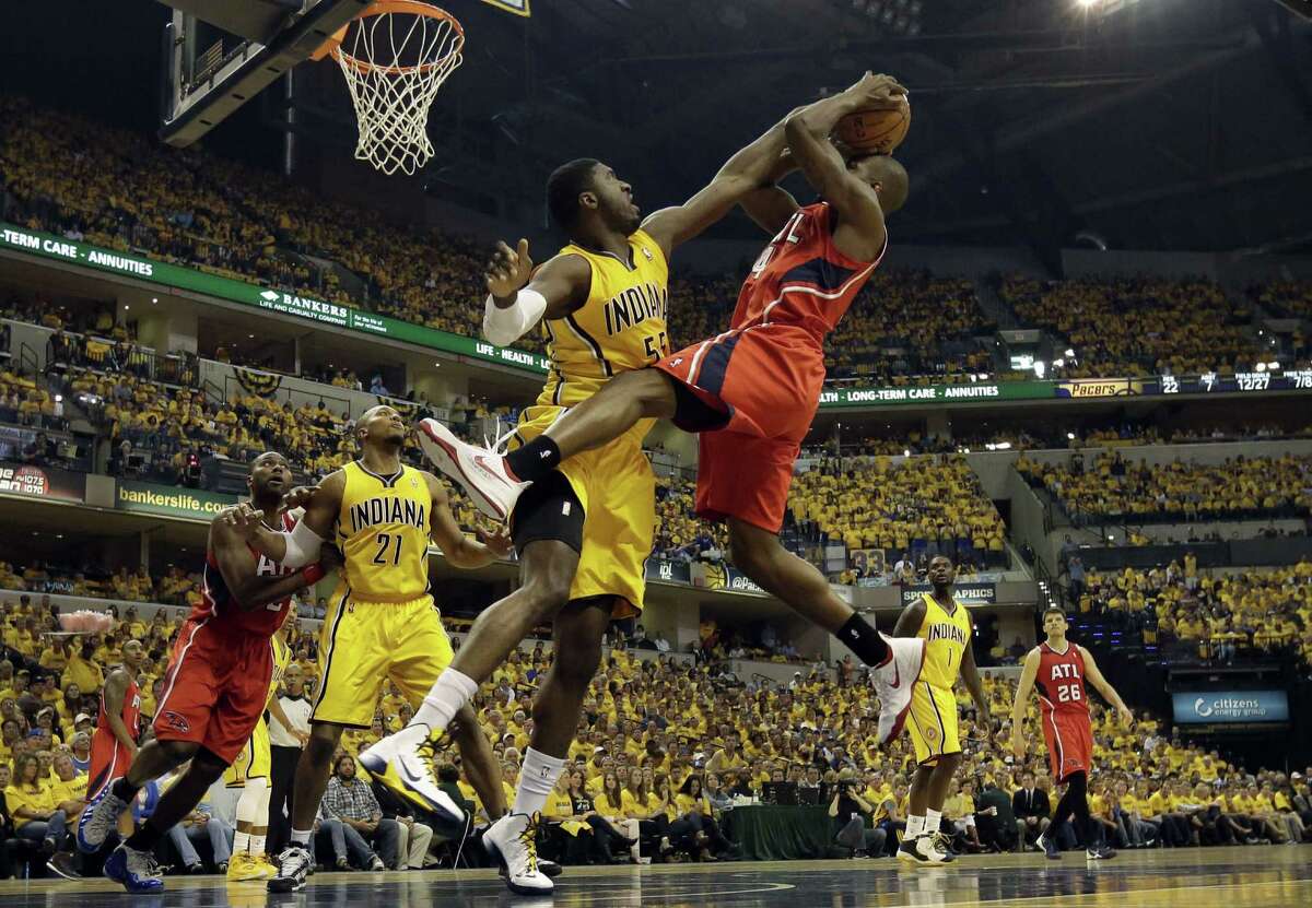 Pacers center Roy Hibbert (front left) tries to block the shot of Hawks forward Paul Millsap during the first half. Hibbert, who had just 20 points in the first six games of the series combined, contributed 13 points, seven rebounds and five blocks Saturday.