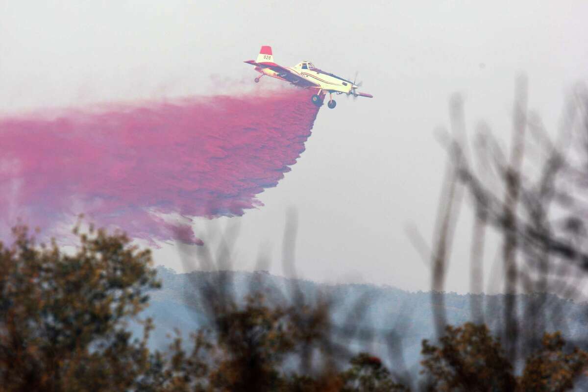 A plane drops fire retardant as several area fire department battle a wildfire at Camp Stanley off Ralph Fair Road, Wednesday, Sept. 7, 2011. The fire forced the evacuation of a small area of Fair Oaks Ranch but was under control by early evening.