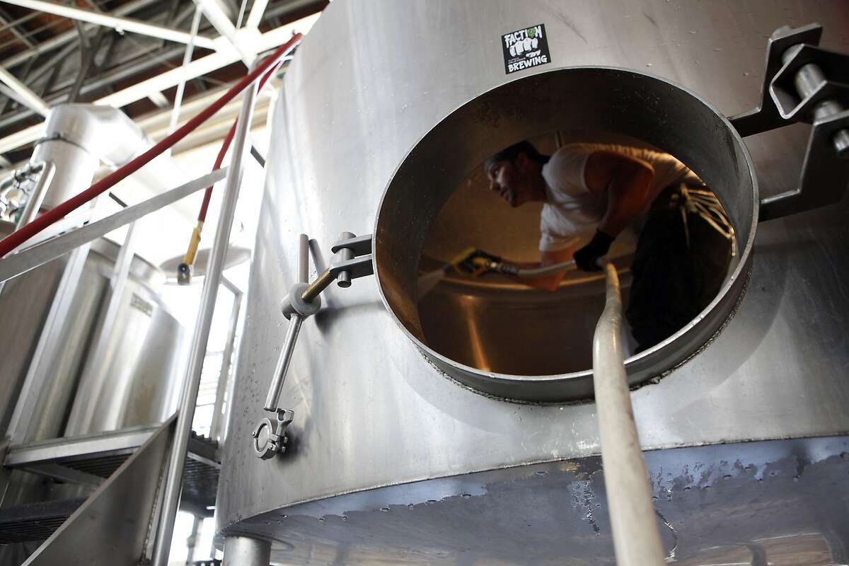Assistant Brewer Chris Villamediana cleans the inside of the Mash Kettle at Faction Brewing Company in Alameda, CA, Wednesday May 7, 2014.