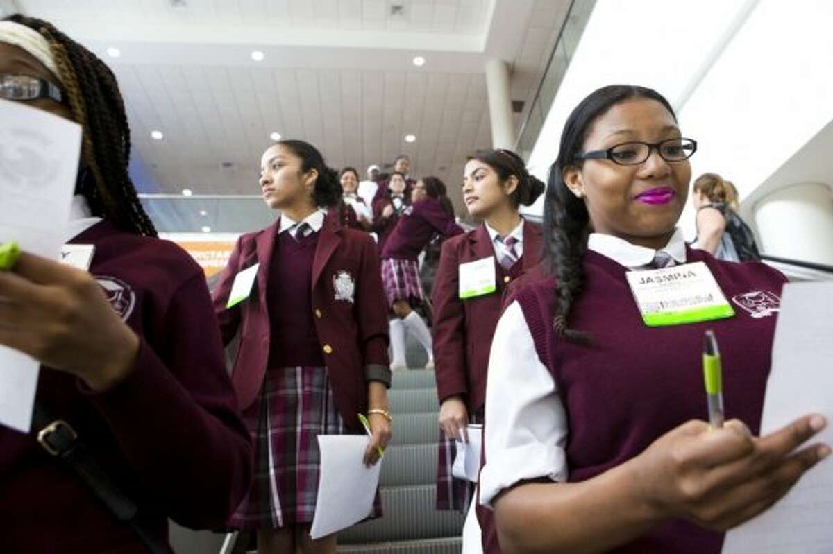 Jasmina Thomas, right, a Young Women's College Preparatory Academy student revises a list of questions as she and her classmates take the escalators to the conference exhibition floor as part of the High School STEM event, Thursday, May 8, 2014, in Houston.