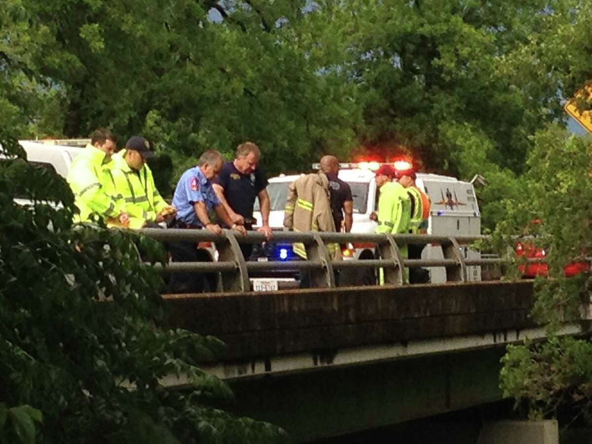 Emergency personnel watch from a bridge on Eisenhauer as others work to recover a body from Salado creek.