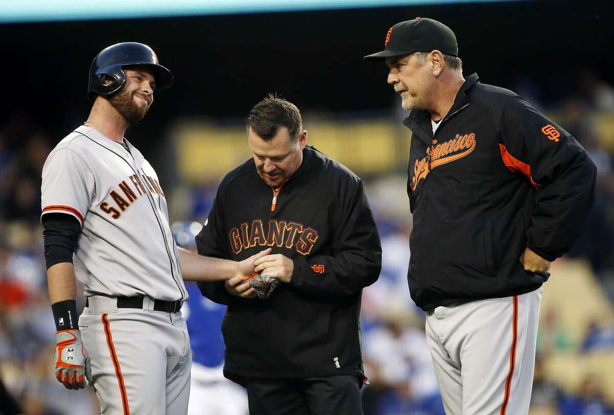 San Francisco Giants' Brandon Belt, left, reacts after being hit by a pitch on his left hand as a trainer and manager Bruce Bochy, right, attend to him against the Los Angeles Dodgers during the second inning of a baseball game, Friday, May 9, 2014, in Los Angeles. (AP Photo/Danny Moloshok)