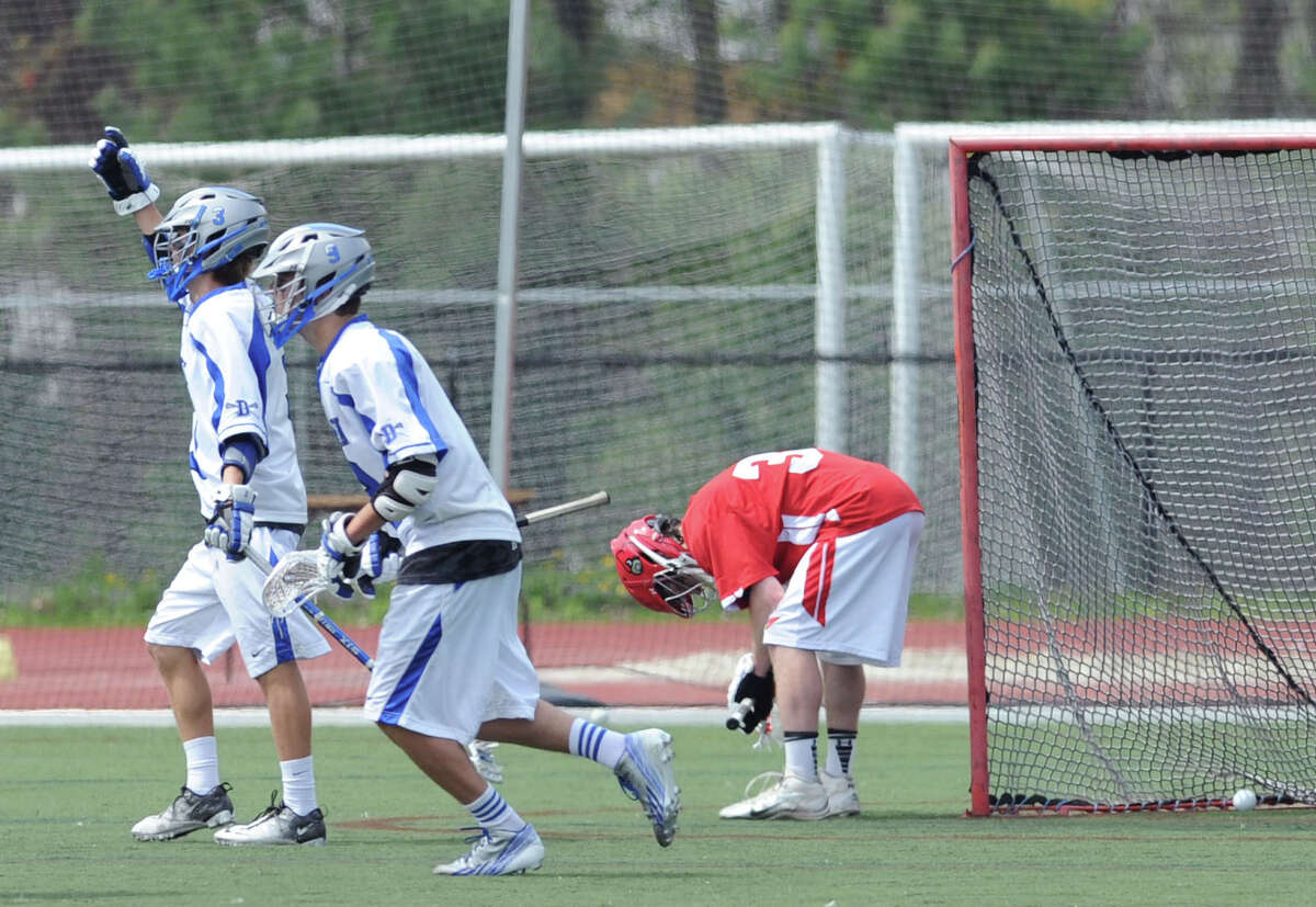 Greenwich goalie Tommy Rogan, right, bows down as the ball shot by Darien's John Reed comes to rest in the net for a 4th quarter goal during the boys high school lacrosse match between Darien High School and Greenwich High School at Darien, Saturday afternoon, May 10, 2014. Celebrating Reed's goal are Darien teammates, Colin Minicus, left, and Owen Koorbusch, center. Darien remained undefeated, winning the match over Greenwich, 10-4.