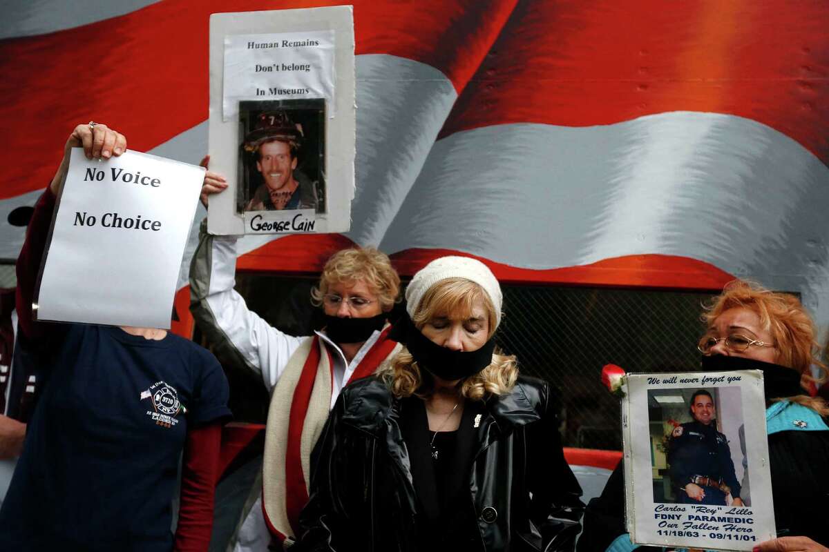 Family members of victims of the Sept. 11, 2001 attacks tie black gags over their mouths in protest of the transfer of unidentified remains of those killed at the World Trade Center from the Office of the Chief Medical Examiner to the World Trade Center site, Saturday, May 10, 2014, in New York. The remains will be transferred to an underground repository in the same building as the National September 11 Memorial Museum. (AP Photo/Jason DeCrow) ORG XMIT: NYJD107