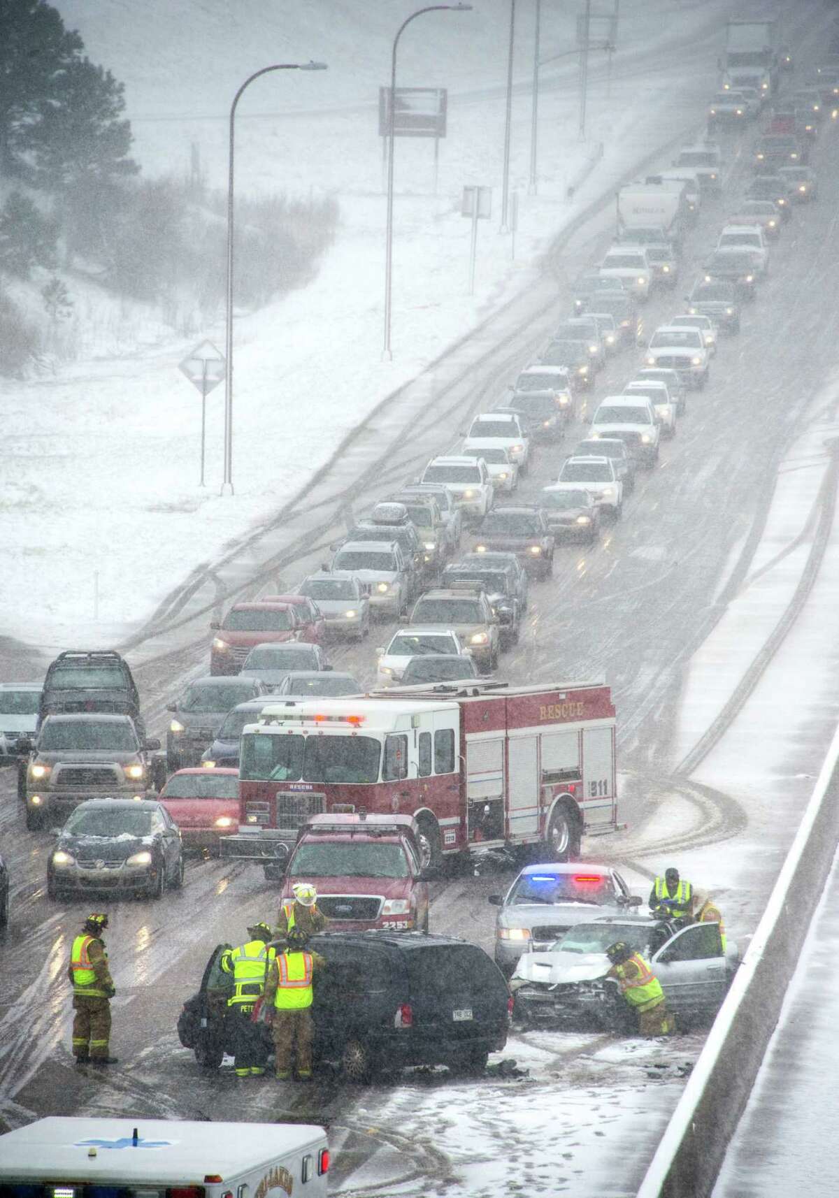 Firefighters work the scene of a two car injury accident that was one of many that slowed traffic on I-25 at the Monument exit north of Colorado Springs, Colo. as a spring snowstorm swept through Colorado Sunday, May 11, 2014. (AP Photo/The Gazette, Mark Reis)