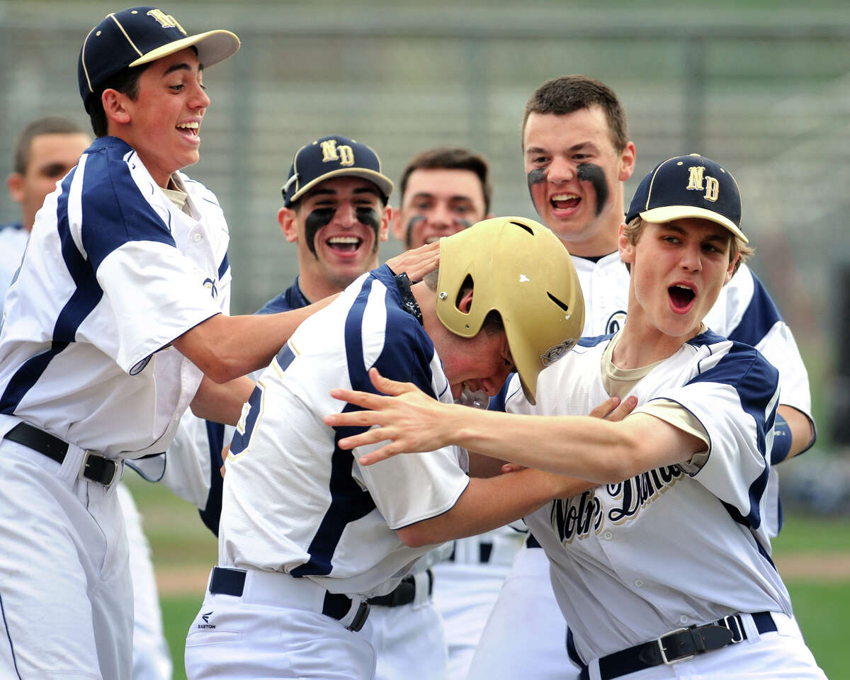 Notre Dame of Fairfield's Brendan Barger, center, is swarmed by teammates after his 7th inning hit drove in the game winning run during a high school baseball game against Bunnell, in Fairfield, Conn. May 12, 2014.
