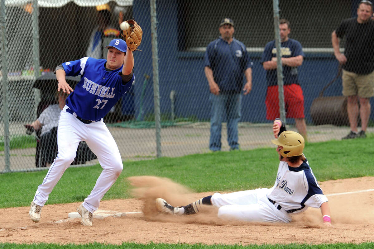 Notre Dame's Spencer Bassett slides safely into third base ahead of a throw to Bunnell's Justin Lasko during high school baseball action, in Fairfield, Conn. May 12, 2014.