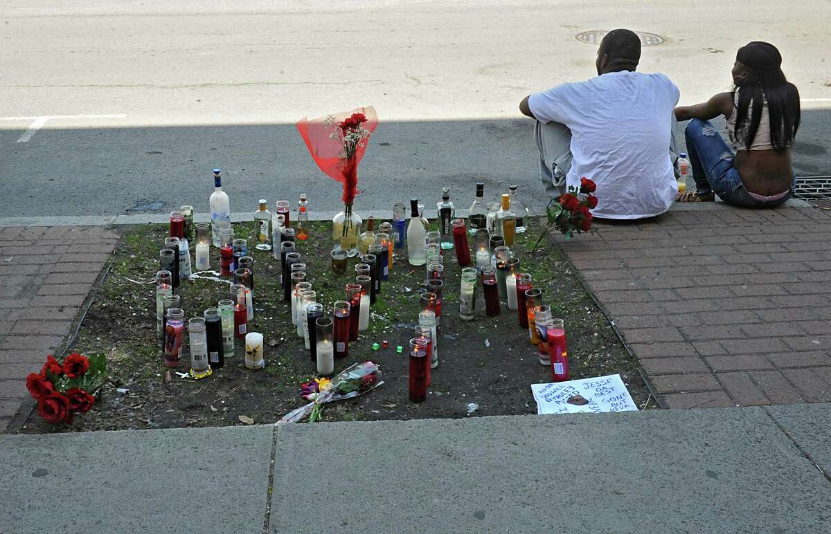 Mourners sit next to a memorial of lighted candles and balloons Monday, May 12, 2014, where 23-year-old Jesse Overton of Albany was gunned down early Sunday near the intersection of Madison Avenue and South Pearl Street in Albany, N.Y. (Lori Van Buren / Times Union)
