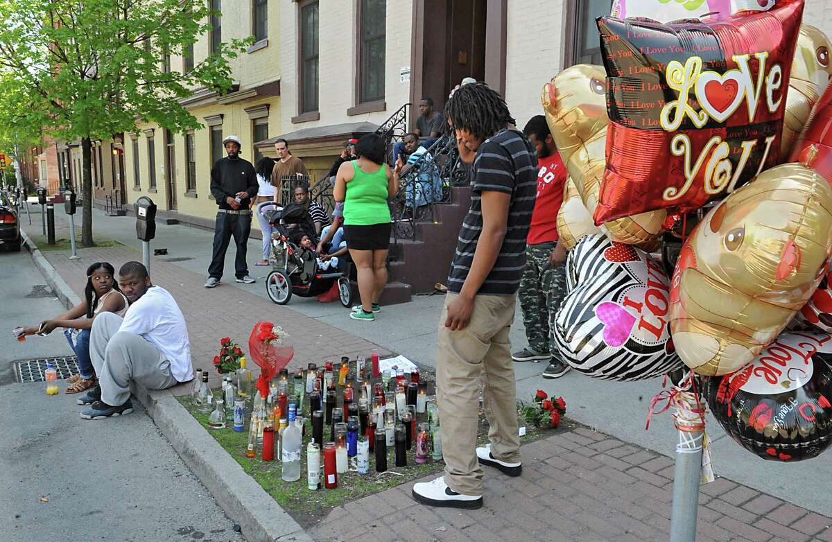 Chaikh Nass of Albany, center, looks over a memorial of lighted candles and balloons Monday afternoon, May 12, 2014, at the place where his friend, 23-year-old Jesse Overton of Albany, was gunned down early Sunday near the intersection of Madison Avenue and South Pearl Street in Albany, N.Y. (Lori Van Buren / Times Union)