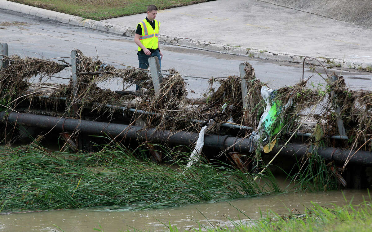 Bjorn Boentges, a project manager for Bexar County Flood Control, walks past debris Tuesday May 13, 2014 stuck in a bridge railing at a low water crossing at Vicar and Perrin Beitel. Heavy rain swept through the San Antonio area causing numerous road closures. Boentges was taking pictures in the area as a reference for future flood control projects.