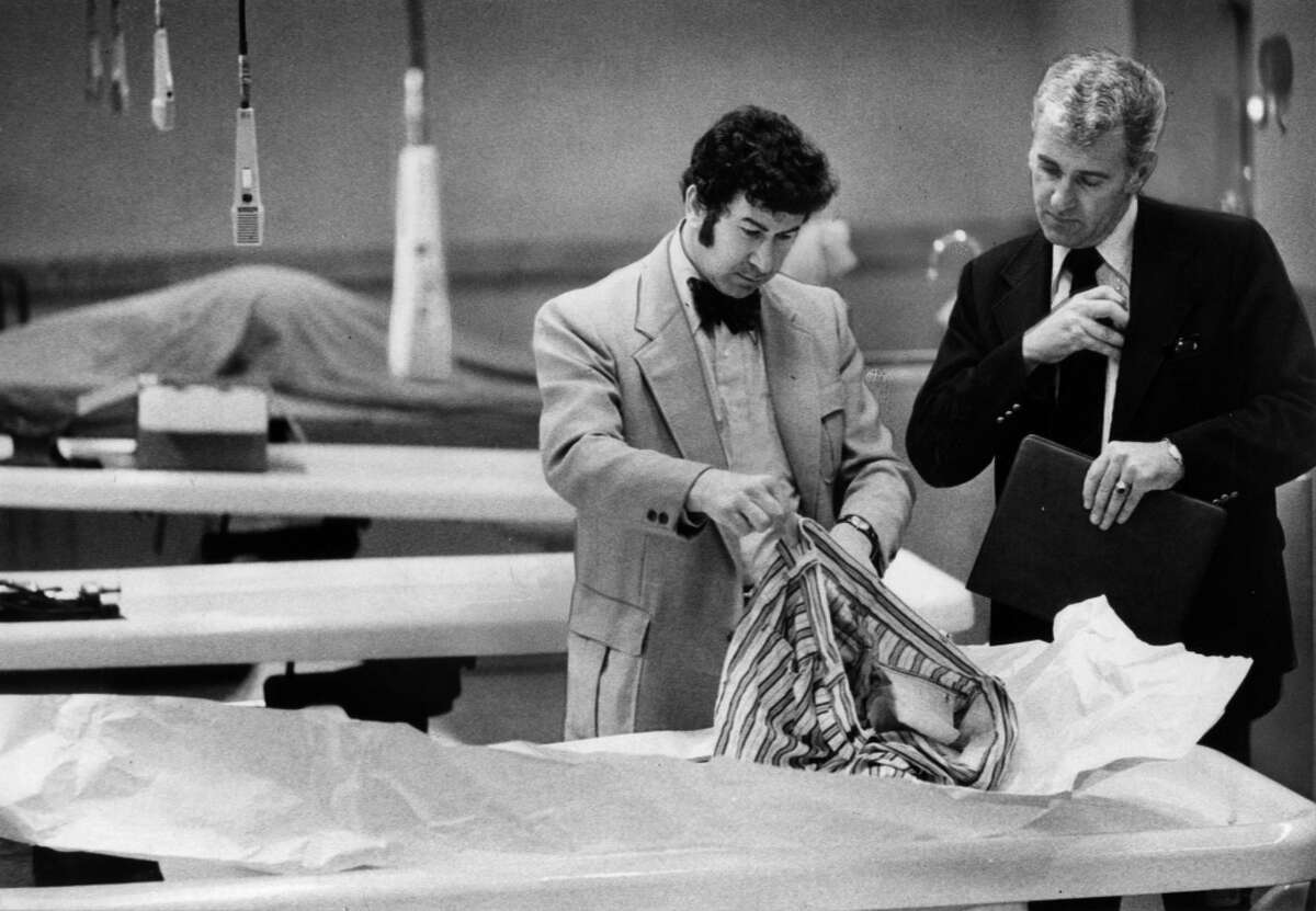 In this photo from March 29, 1974, San Francisco homicide inspectors David Toschi, left, and William Armstrong go through a murder victim's clothes at the morgue in the Hall of Justice in San Francisco. The Zodiac killer is blamed for at least five murders in 1968 and 1969 in the San Francisco Bay Area.