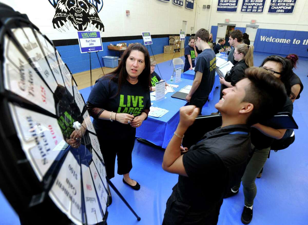 Mike Baculima, 17, right, reacts to the results after spinning "the wheel of reality" as Sikorsky employee Patricia Schulte of Milford, Conn. watches during a financial seminar Tuesday Tuesday at Abbott Technical School. Volunteers from Sikorsky Credit Union spend the morning teaching kids at Abbott Techl all about the ins and outs of personal finance, Tuesday, May 13, 2014.