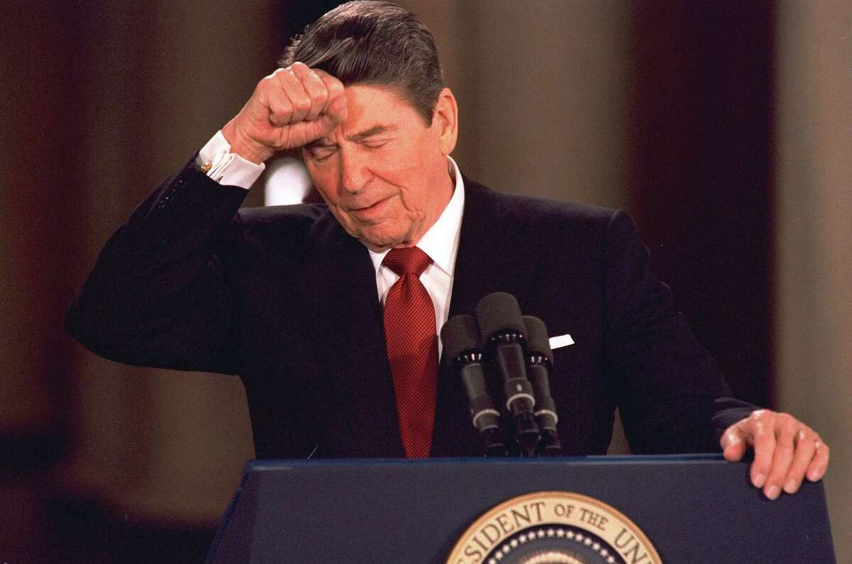 FILE - In this March 19, 1987 file photo, President Ronald Reagan taps his forehead at the White House while responding to a reporter's question during a news conference at which he said he never deliberately lied to the public, despite admitting to a misstatement about Israeli involvement in the Iran-Contra affair. In a 1986 radio address admitting to missteps in the Iran-Contra scandal, the president famously said "mistakes were made" - a passive acknowledgement of wrongdoing that didn't directly implicate anyone.