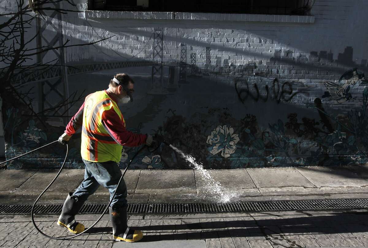 Steve Mahoney sprays disinfectant on the ground before using a power washer to clean Jack Kerouac Alley for the Department of Public Works in San Francisco, Calif. on Wednesday, May 14, 2014. Supervisor Scott Weiner is seeking to boost the department's budget and add additional cleaning crews to battle a growing problem of urine and feces covering streets and sidewalks throughout the city.