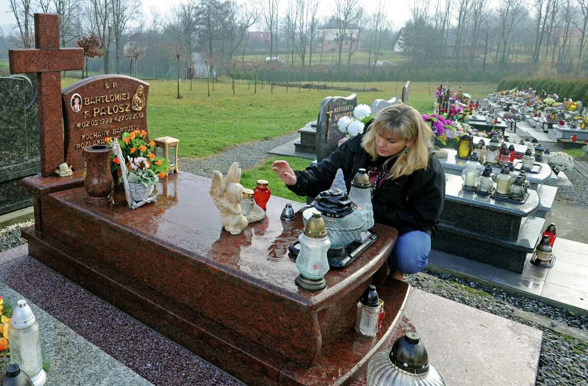 Anna Palosz lights a candle on the grave of her son Bart, at the cemetery in Kalna, Poland, Friday, Nov. 22, 2013.
