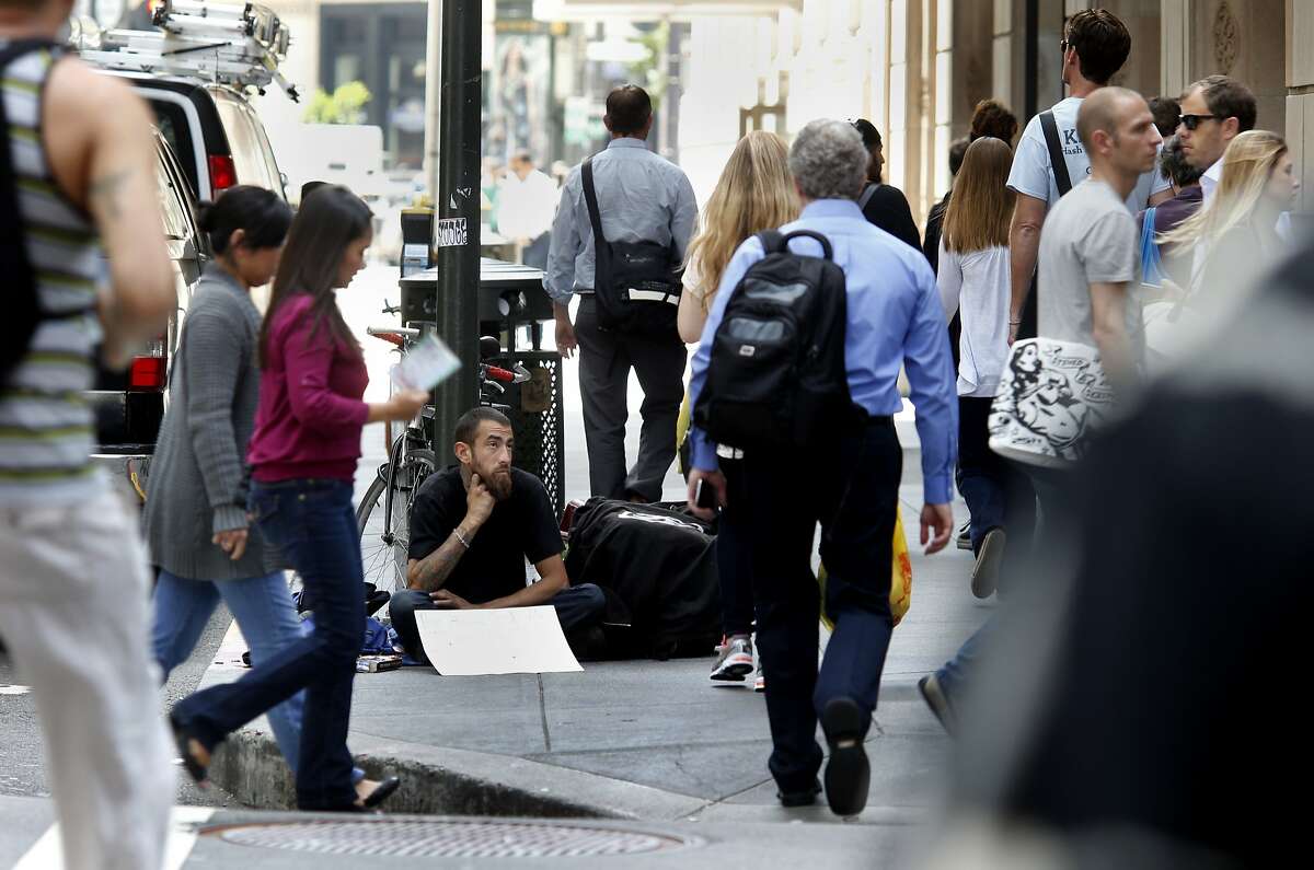 On Montgomery Street, a man asking for money watches people as they crowd the street and sidewalk Thursday May 15, 2014 in San Francisco, Calif. The San Francisco Human Services Agency has put out a report about income inequality which is growing at a startling pace, where the rich are getting richer and the poor are getting poorer. The middle class seem to be leaving.