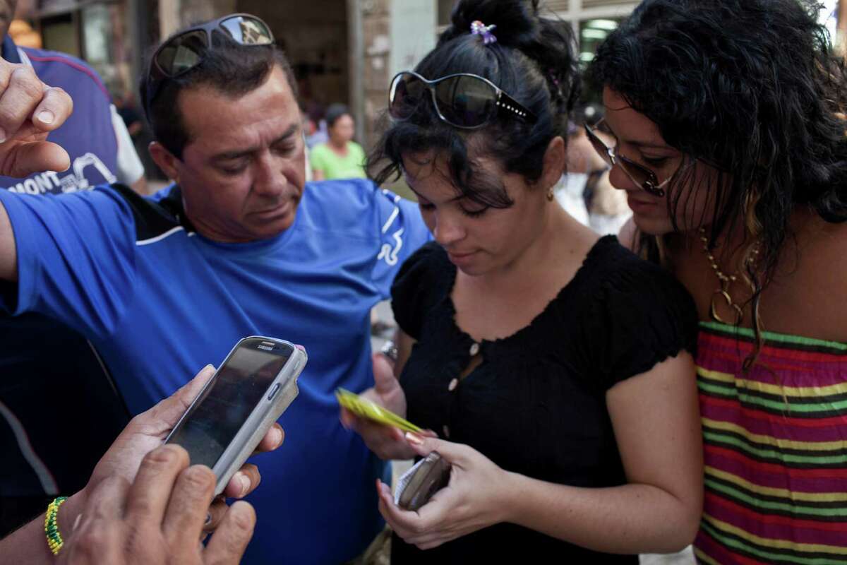 People try to connect to a server as they wait - and wait - with other customers outside the offices of the state telecom monopoly Etecsa in Havana.