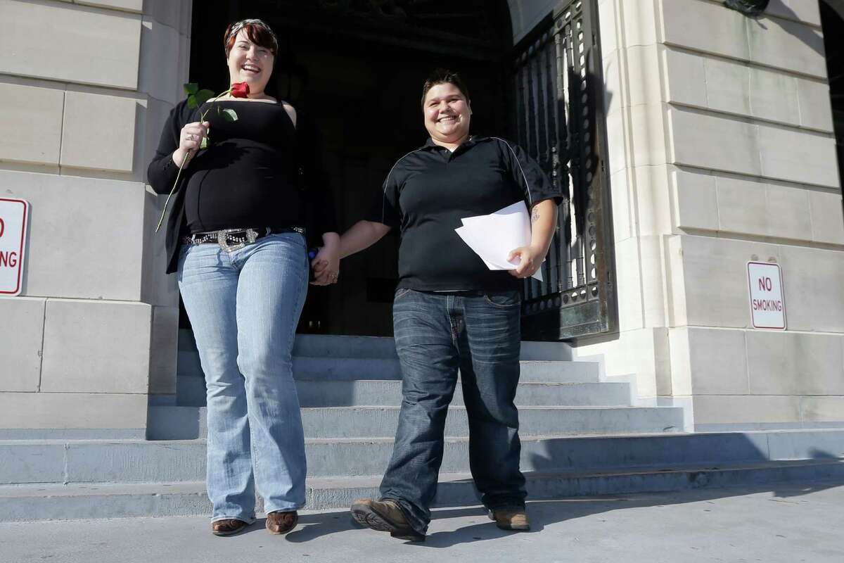 Lauren Castator, left, and Brittany Castator of Lake Jackson, Texas, walk from the Pulaski County Courthouse in Little Rock, Ark., after being married Friday, May 16, 2014. Marriage licenses were issued to same-sex couples in the county Friday. (AP Photo/Danny Johnston)