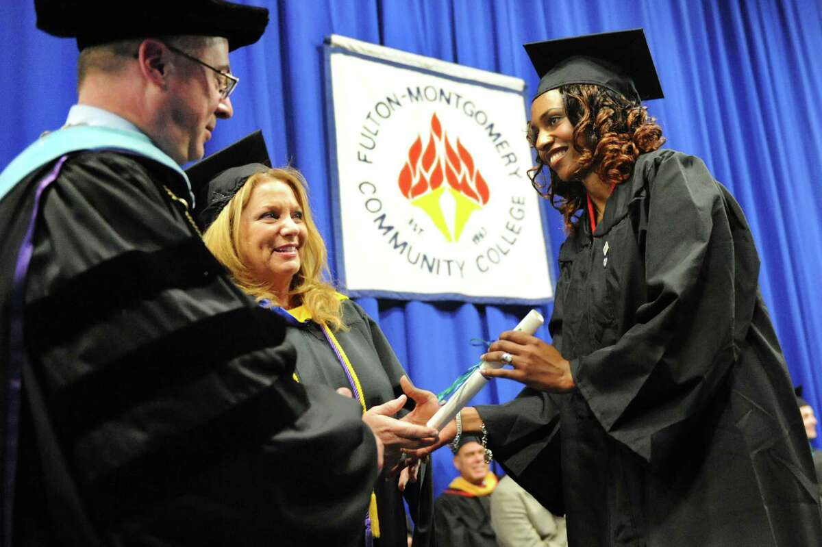 Graduate Grace Rutagengwa, right, receives her diploma from college presiden Dustin Swanger, left, and her mother Robin DeVito on Friday, May 16, 2014, at Fulton-Montgomery Community College in Johnstown, N.Y. (Cindy Schultz / Times Union)