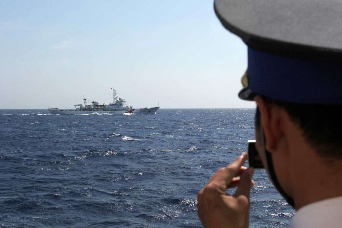 In this photo, taken Thursday, an officer on board Vietnam Coast Guard vessel 4033 films a Chinese ship sailing in waters claimed by both countries in the South China Sea. Their rivalry dates back centuries.