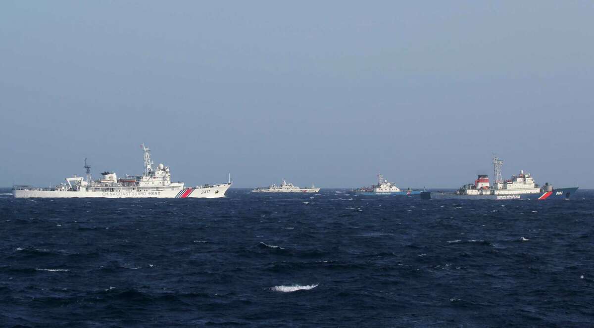In this Thursday, May 15, 2014 photo, China Coast Guard vessels, left in white, and Vietnam Coast Guard vessel, in blue, sail in the waters claimed by both countries in the South China Sea. China's deployment of an oil rig off Vietnam's coast has prompted a tense sea standoff and touched off deadly anti-China rioting. The conflict pits two neighbors with very similar governments but whose people bear ill feelings rooted in a rivalry that dates back centuries and has occasionally burst out into armed conflict. (AP Photo/Hau Dinh)